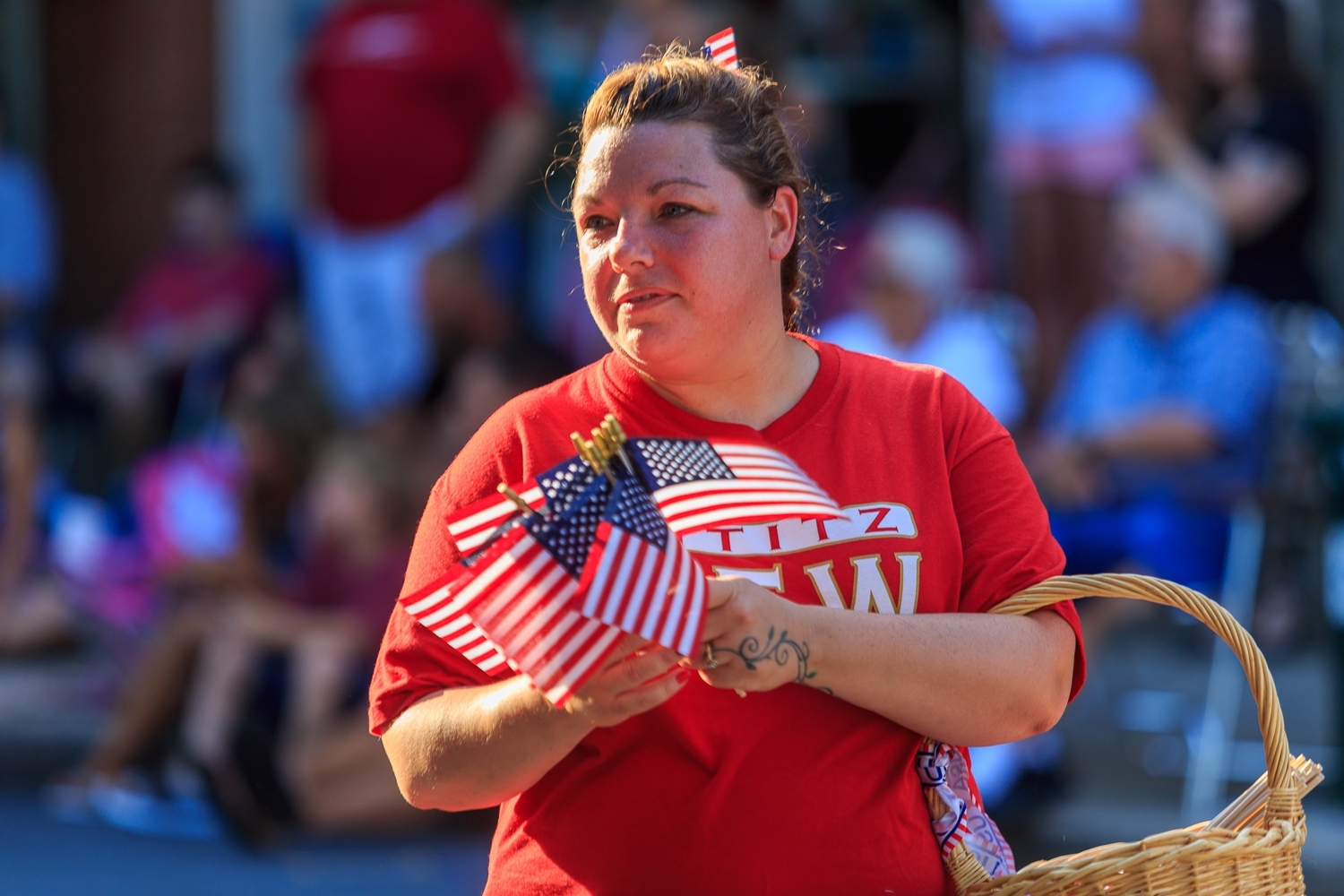 Lititz, PA / USA - July 3, 2017:   A woman hands out  US flags during a patriotic parade in a small American town at a 4th of July Independence Day celebration.