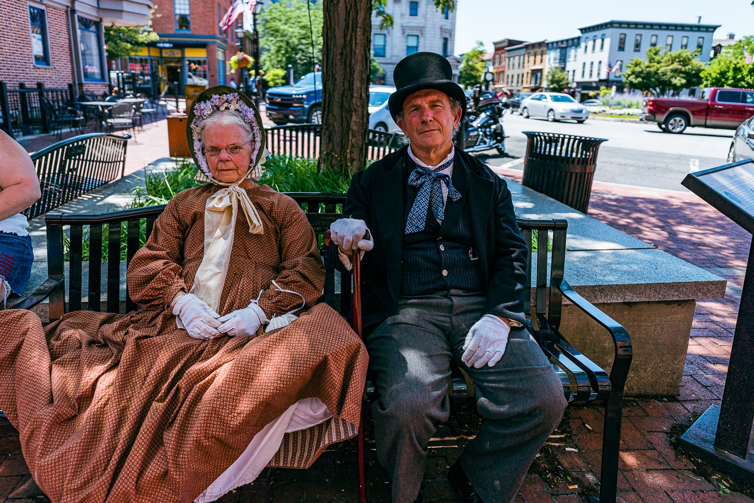 Gettysburg, PA, USA – July 3, 2022: A pair of historical reenactors sit in the shade in the downtown square in period clothing over the July 4th celebration in Adams County, PA.